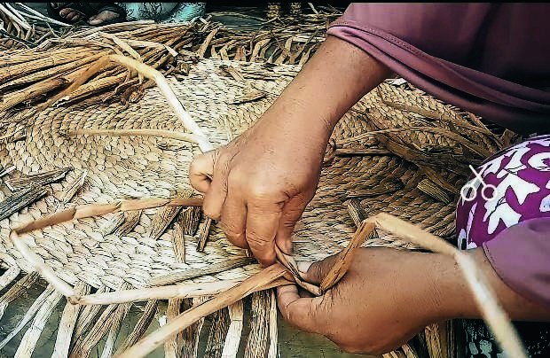 Artisan weaving natural fiber by hand